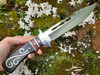 enchanted witch's ritual athame being held in a hand with a background of moss and white flowers.