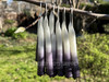 Six pairs of power, all-purpose manifestation and protection spell taper candles hang off a branch demonstrating variations.