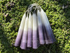 Several pairs of power, all-purpose manifestation and protection spell candles rest on a bed of greenery.