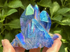 Close-up Tanzine Aura Quartz cluster crystal on hand in sunlight with greenery, vivid blue violet aura quartz stone for meditation.