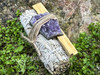 One sage and palo santo cleansing kit angled to the left, resting on greenery, showing size with the amethyst cluster clearly visible.