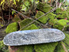 Orthoceras fossil double stick incense burner with two incense sticks resting on moss-covered bricks, shown from the front and slightly above with greenery in the background.