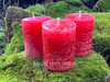 Three Dragon's Blood Protection Votive Candles stand on moss covered bricks. 