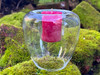 One floating handblown glass votive and tealight candle holder rests on moss-covered brick. Inside the candle cup rests our dragon's blood protection votive candle.