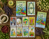 The herbal tarot deck box shown from above with several cards laid out with the book to the right surrounded by herbs.