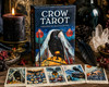 Crow Tarot deck shown from the front with several cards fanned in the front of the box surrounded by crystals and candlelight