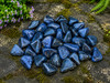 Natural Dumortierite tumbled stones displayed on moss in a woodland-inspired outdoor setting.