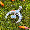 Rainbow Moonstone sterling silver crescent moon pendant with two bezel-set cabochons showing natural blue flash, displayed on green moss.