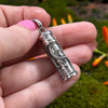 Back of sterling silver prayer bottle pendant held in hand, showing scrolling silverwork and the scale of the 1.25 inch vial.