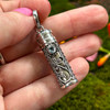 Sterling silver Blue Topaz prayer bottle pendant held in hand to show its compact 1.25 inch size and detailed front silverwork.