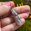 Angled in-hand view of sterling silver intention bottle pendant showing faceted Blue Topaz, decorative side details and removable cap.
