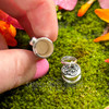 Removable cap of sterling silver intention bottle shown open fingers hold the vial, displaying the interior of the pendant.