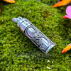 Reverse side of sterling silver intention bottle pendant showing the raised scrolling silverwork and cylindrical removable cap.