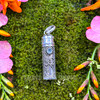 Close view of sterling silver prayer bottle pendant featuring faceted Blue Topaz and detailed scrolling silver ornamentation.