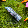 Side and back view of sterling silver Amethyst prayer vial showing the decorative scrollwork surrounding the cylindrical pendant.