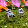 Open sterling silver Garnet intention vial resting on moss showing the .925 silver stamp with removable cap beside it and faceted red Garnet visible at the top.