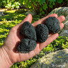 Extra large natural tektite stones held in hand, showing their substantial size, rugged texture, and natural variation.