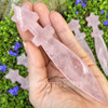 Close-up of a Rose Quartz crystal athame held in hand, showing natural pink variation, polished blade, crossguard, and star-shaped handle.