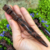 Mahogany Obsidian crystal athame held in hand to show its 5.25 inch size, polished pointed blade, crossguard, and dark patterned stone.