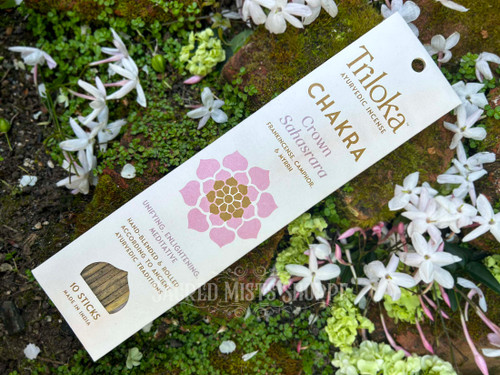 One package of Crown Chakra Handmade Incense surrounded by white flowers with the full package showing at an angle.