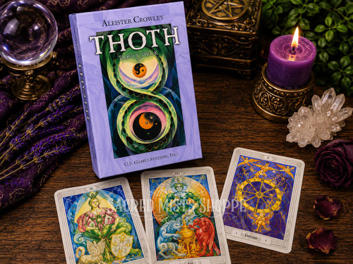 Aleister Crowley Thoth Tarot Deck Premier Edition displayed with three Thoth tarot cards, crystal ball, amethyst, quartz crystals, candle, and occult altar décor.