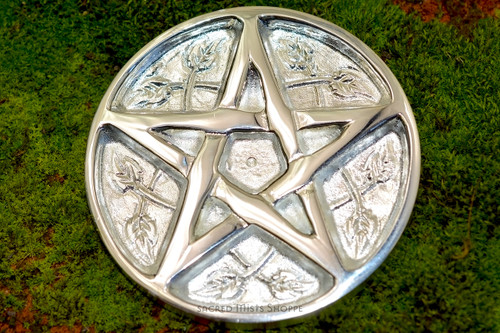 One pentacle and leaf altar paten rests on a bed of moss.