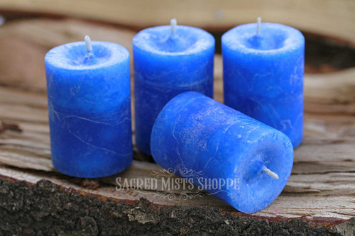 Four blue inner balance herbal spell votive candles on a piece of wood.