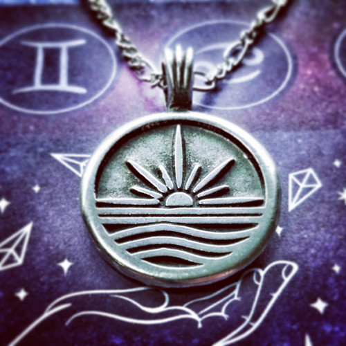 one sunrise pendant necklace lying on an astrology themed altar cloth. Sunrise Necklace for Dawn Magick, Solar Energy, God, Goddess, New Beginnings, Affirmation, Sun, Intention, Pagan Jewelry, Witchcraft