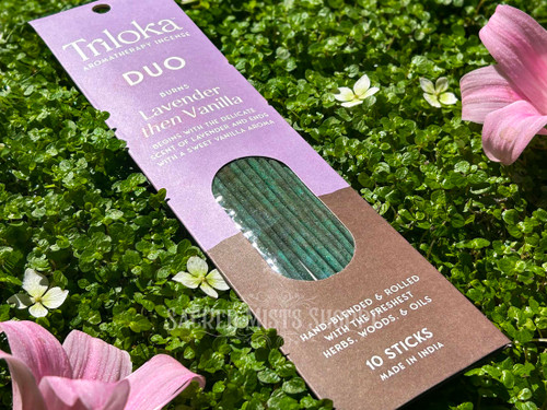 One package of Lavender & Vanilla Duet Masala Stick Incense angled to the left on a bed of greenery with white and pink flowers. This is ideal for calming energies, meditation, and creating sacred space.