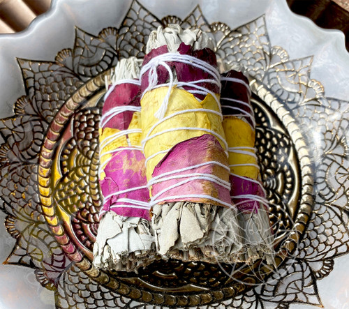 White Sage and Roses Smudge Stick Bundle. Our organic white sage and rose smudge bundle is perfect for purification with the added energetic blessings of real red and yellow rose petals. The roses add the blessings of love, happiness, and new beginnings to the white sage and, as a smudge, is perfect for energy clearing and cleansing while ensuring that your positive intentions fill the energy void left behind during your clearing which is an important step in the process. Our white sage is grown and harvested in summer. Traditionally used by the North American Indians as a means of purification. When lit, the smoldering bundle of sage and roses produce a highly aromatic fragrance. Great for ritual, incense, or purification use. Each one of these smudge sticks is hand wrapped with love and sacred intention.