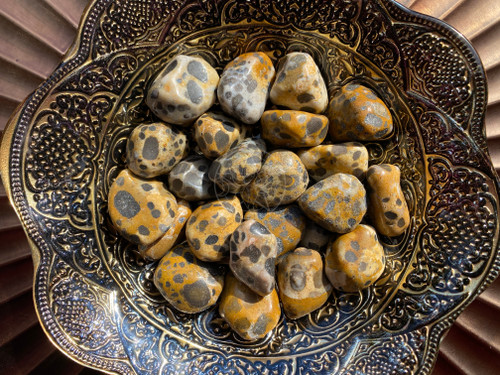 several aa quality cheetah jasper stones are in a large bowl with a charger plate in the background.