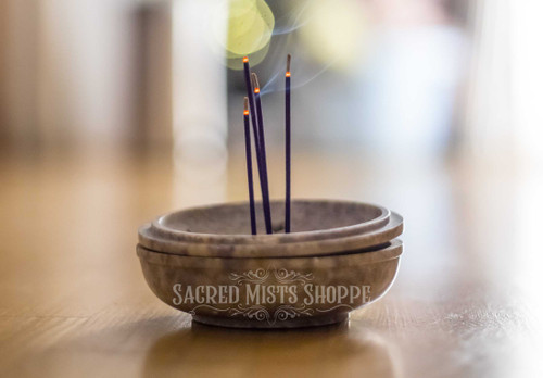 Koh incense burning in a soapstone bowl on a wood table