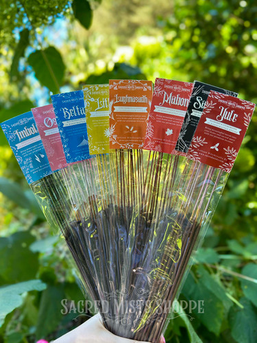 Eight packages of Sabbat Incense, one for each Sabbat: Imbolc, Ostara, Beltane, Litha, Lughnasdadh, Mabon, Samhain, Yule held in a hand like a bouquet of flowers with greenery behind. Perfect for spells, rituals, celebrations, home fragrance.