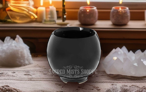 One dark moon incense and smudge bowl standing on a table with crystal clusters to either side.