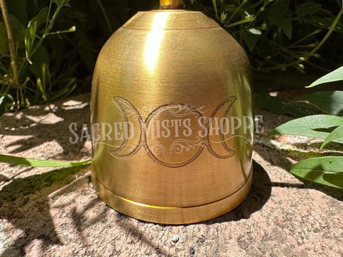 A bright gold satin finish brass altar bell with an engraving of the triple moon symbol. The handle features a crescent moon.