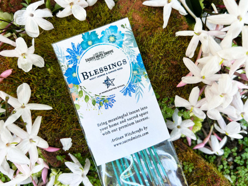 One pack of Blessings Handmade Incense lying on a bed of flowers and brick. Fragrance notes for this incense are night-blooming jasmin, damask rose, and creamy musk.