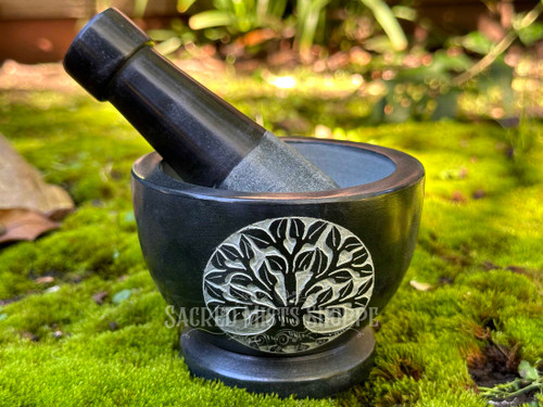 black tree of life mortar with pestle sitting inside made from hand-carved soapstone