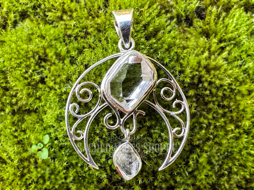 sterling silver crescent moon filigree design with Herkimer diamond set and Herkimer diamond drop lying atop a bed of moss