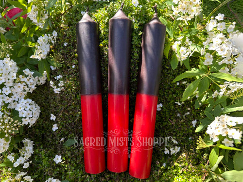 three black and red reversing candles laying on greenery and flowers