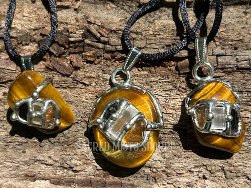 Three One Tigers Eye Clarity Pendant Necklaces with hypersthene, selenite, and rutilated quartz displaying three possible layouts, laying on a piece of wood. Perfect for clarity, confidence, spiritual insight, focus, and empowerment.