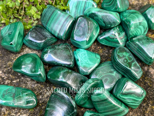 Close-up of polished malachite tumbled stones showing detailed green banded patterns on rock, crystal for protection and balance.