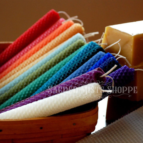 An array of hand-rolled beeswax mini candles in vibrant colors are angled to the side in a basket with a block of beeswax in the background.