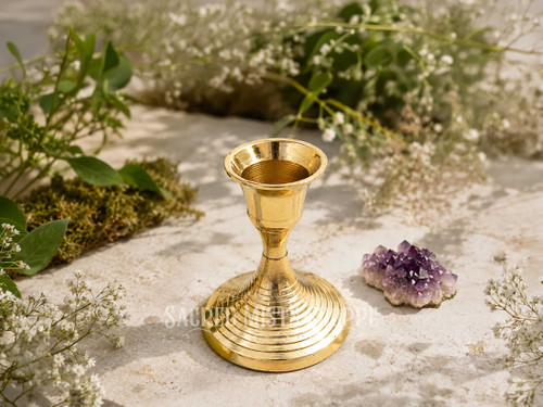 Polished brass taper candle holder with concentric ring base for standard taper candles displayed beside an amethyst crystal outdoors in warm natural sunlight.