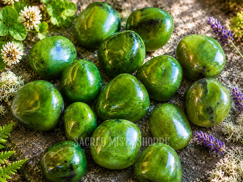Close-up of Natural Nephrite Jade tumbled stones displaying rich green hues, glossy polished surfaces, and subtle natural mineral variations.