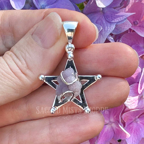 Grape Chalcedony pentagram pendant held in hand against green leaves, showing the scale, polished sterling silver setting, and purple crystal cluster.