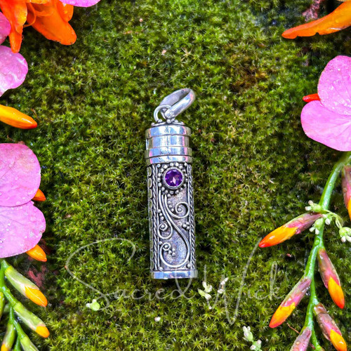 Sterling silver Amethyst intention and prayer bottle pendant resting on green moss with pink and orange flowers.