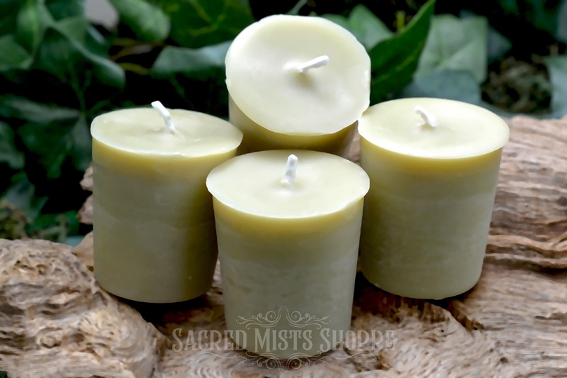 Four bayberry votive candles stand on raw wood with greenery in the background.