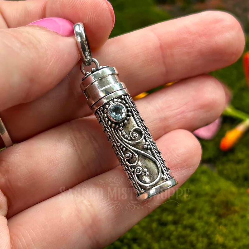 Sterling silver Blue Topaz prayer bottle pendant held in hand to show its compact 1.25 inch size and detailed front silverwork.