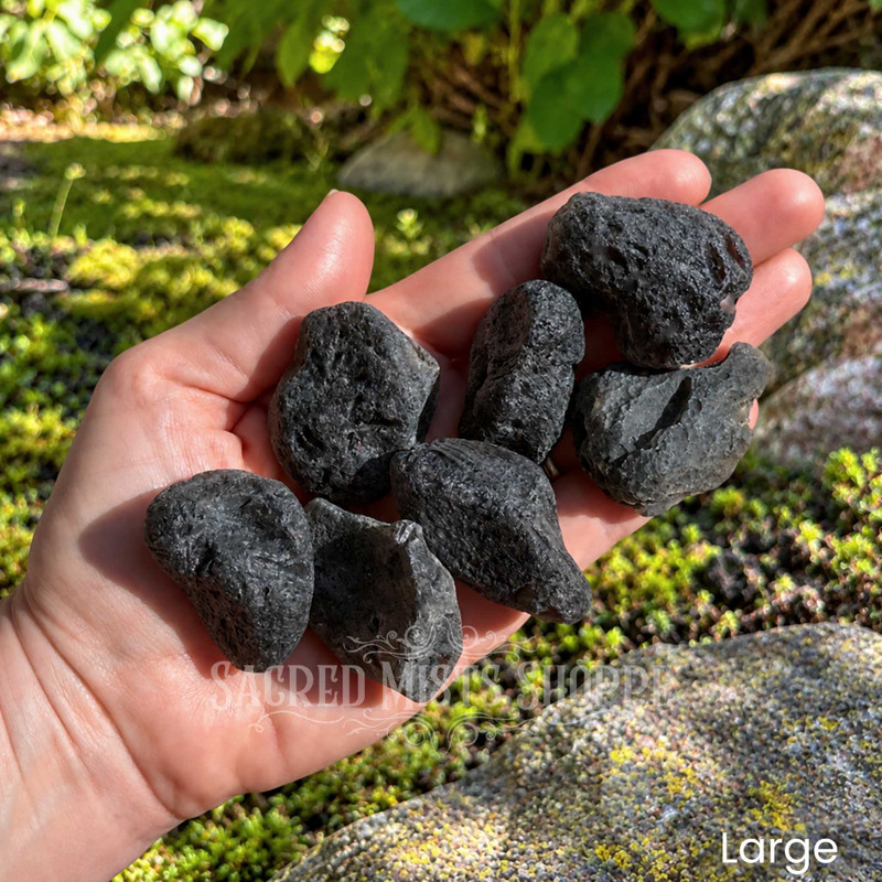 Large natural tektite stones held in hand, showing their irregular shapes and dark textured surfaces.