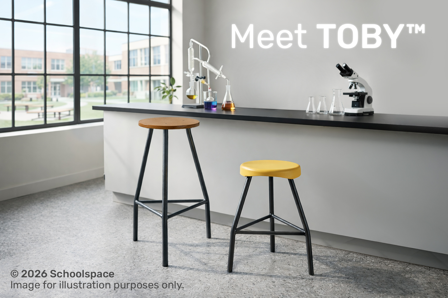 Laboratory stools with dark grey metal frames and round plastic or wooden seats placed beside a science lab workbench in a modern classroom setting.